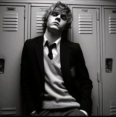 a man in a suit leaning against lockers with his head resting on his hands