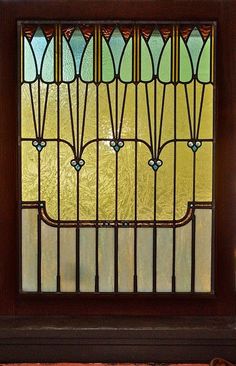 a close up of a stained glass window on a door frame with a teddy bear sitting in front of it