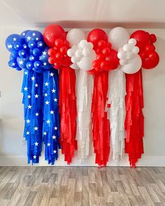 red, white and blue balloons are hanging on the wall