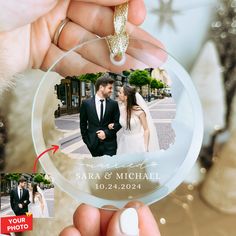 a person holding a glass ornament with a wedding photo on the front and side