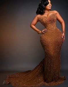 a woman in a brown gown posing for the camera with her hands on her hips