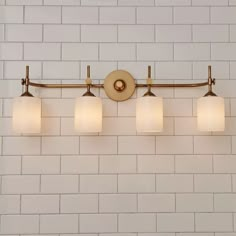 a bathroom light with four lights on it and white brick wall in the back ground