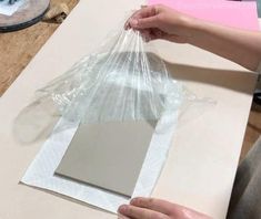 a person holding a plastic bag over a piece of paper on top of a table