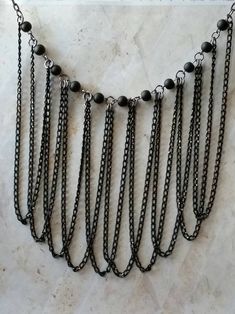 This draped bib chain necklace in gunmetal and black is one of my newest projects. It features matte black glass beads and multiple lengths of draped chain. The necklace has 11 8mm matte black beads wired onto eye pins and connected with gunmetal-toned jump rings. Attached to the jump rings are ten 9 inch lengths of black chain. The chains are draped and they hang down beautifully. I finished the necklace with a black chain and a lobster claw clasp for easy use. The necklace is 20 inches long no Bohemian Black Chain Necklace With Adjustable Chain, Black Bohemian Chain Necklace With Adjustable Chain, Bohemian Black Adjustable Chain Necklace, Black Gothic Jewelry With Beaded Chain, Black Metal Dangle Chain Necklace, Black Metal Jewelry With Ball Chain, Black Bohemian Necklace With Chain, Bohemian Black Chain Necklace, Bohemian Black Metal Chain Necklace