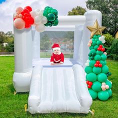 an inflatable christmas tree and balloon arch with a baby on it, surrounded by balloons