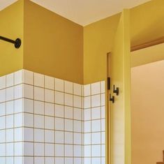 a bathroom with yellow walls and white tiles on the wall, along with a black door