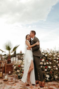 a bride and groom embracing each other in front of flowers