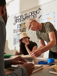 an older man and young woman working together at a table