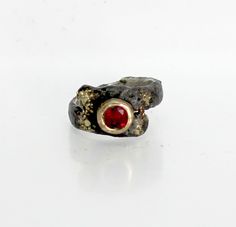 I set a 6mm round faceted ruby in a 14k gold setting. Around the setting I fused 18k gold for interest and contrast. Ruby is the birthstone for July. Casual  or formal wear ring. The band is sterling silver with a fused texture. A black patina was used to make the various elements stand out. Over time the patina will wear off the high points leaving a pleasing two tone effect. The band averages 11mm at the top and 5mm wide by 2mm thick. I designed and made this ring. You can order this ring in any size. Free shipping in the USA. Hand Forged Ruby Ring, Hand Forged Ruby Ring In Red, Hand Forged Red Ruby Ring, Hand Forged Round Ruby Rings, Hand Forged Red Jewelry For Anniversary, Hand Forged Ruby Ring Jewelry, Elegant Hand Forged Round Ruby Ring, Hand Forged Ruby Ring For Anniversary, Hand-forged Round Ruby Ring Gift