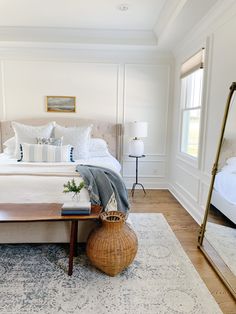 a bedroom with white walls and wood flooring has a large bed in the center