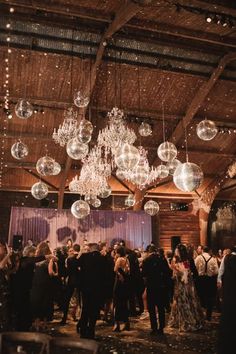 a large group of people standing around in a room with chandeliers hanging from the ceiling