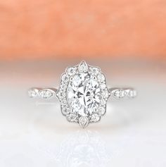 a white gold ring with an oval cut diamond in the center and pave set shoulders