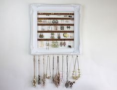 a white frame with many different necklaces hanging from it's sides on a wall