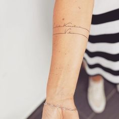 a woman's arm with a tattoo on it and a chain around the wrist