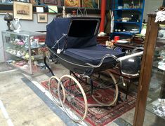 a baby carriage sitting on top of a rug next to a glass case filled with items