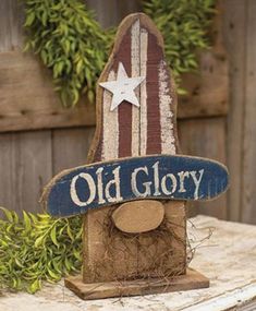 an old glory sign sitting on top of a wooden table next to a planter