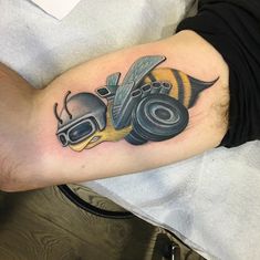 a man with a tattoo on his arm has a bee and headphones in it