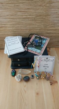 an open black suitcase sitting on top of a wooden floor next to two cards and other items