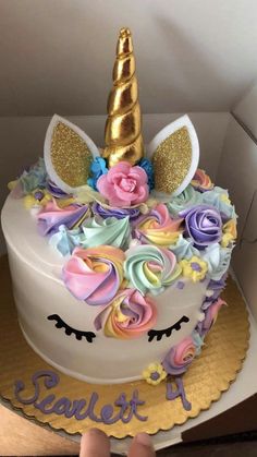 there is a cake decorated with flowers and a unicorn's head on top, in a box