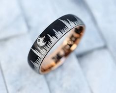 a black and gold wedding ring with an image of the city skyline inlayed to it