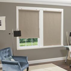 a living room filled with furniture and a window covered in roller shades on the windowsill