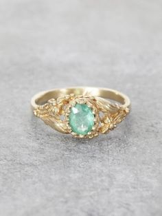 A lush Golden Garden of delicately detailed wildflowers and gracefully winding leaves, reveals a precious, crowned Emerald jewel set in Solid 14K Gold. This would make an exceptional & unique Engagement Ring. Additional gems are also available by request. This extra fine beautiful quality Colombian Emerald measures 6x5.5mm and is approx. .65ct. Ring measures 7.5mm at the front, tapering to a 1.8 mm band. Handcrafted with Love by Elise Perelman in NYC.  We recommend double-checking your ring size Gold Emerald Ring With Nature-inspired Design, Nature-inspired Yellow Gold Gemstone Rings, Elegant May Birthstone Flower Ring With Gemstone, Nature-inspired Gold Emerald Ring, Gold Nature-inspired Round Emerald Ring, Gold Emerald Ring With Nature-inspired Style, Wedding Emerald Ring With Intricate Design, Fine Jewelry Emerald Ring With Intricate Design For Wedding, Fine Jewelry Yellow Gold Emerald Ring With Intricate Design