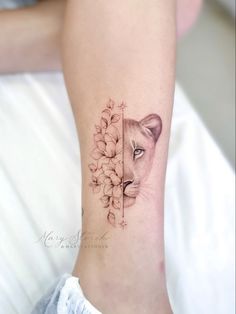 a small tattoo on the ankle of a woman's foot with a lion and flowers