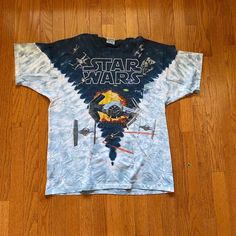 a star wars t - shirt is laying on the floor in front of a wooden floor