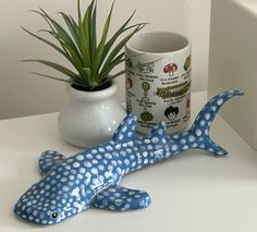 a blue and white fish figurine next to a potted plant on a table