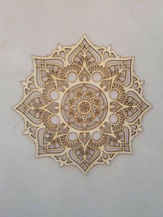 an intricately designed wooden wall hanging on the side of a building with white walls