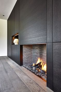 a fire place in the middle of a room with wood flooring and black walls