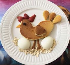 a white plate topped with pancakes and eggs on top of a wooden table next to a painting