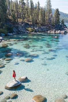 a woman standing on rocks in the water