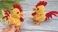 two small yellow and red crocheted chickens sitting next to each other