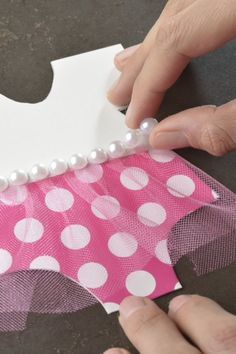 someone is making a pink and white polka dot ribbon