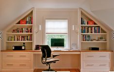 an attic office with built in bookshelves and desk