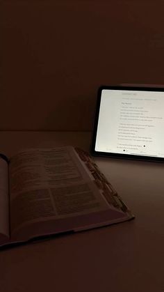 an open book sitting on top of a table next to a computer monitor and keyboard