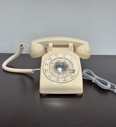 an old fashioned phone sitting on a table with a cord plugged into the telephone