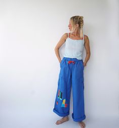 Ultra-flattering high waist cargo pants with drawstring waist from the 90s era. Slightly flared with foldover waistband. Graphic details on front & back that make them special. Very comfortable. In excellent condition. Measurements are taken flat. Fit actual M Waist = 13.5" in (un-stretched) / 34 cm (un-stretched) Hip = 19.5 in / 50 cm Rise = 12.5 in / 32 cm Inseam = 29 in / 73 cm Total length = 40 in / 102 cm Model is 5'6", 26" waist, 36" hip and wears a modern 2-4 Fit guide: It's always a good 90s Style High Waist Blue Pants, 90s High Waist Blue Pants, 90s Style Summer Cotton Cargo Jeans, Retro Cargo Pocket Bottoms For Spring, Retro Wide Leg Cotton Cargo Pants, 90s Style Cotton Cargo Pants For Summer, 90s Style Blue Wide Leg Cargo Jeans, 90s Blue Wide Leg Cargo Jeans, 90s Summer Cargo Style Bottoms