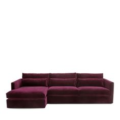 a large purple couch sitting on top of a white floor next to a wooden table