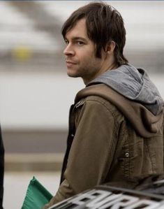 a man with a hoodie is standing next to a luggage bag and looking off into the distance