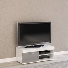 a flat screen tv sitting on top of a white entertainment center next to a wall