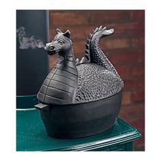 a statue of a dragon on top of a green table next to a black trash can