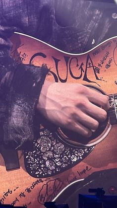 a close up of a person playing an acoustic guitar with writing on the back and sides