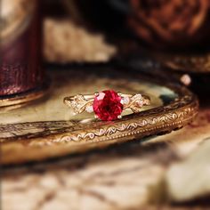 a close up of a ring with a red stone in the middle on a table