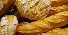 breads and pastries are on display in a bakery case, with powdered sugar sprinkled on top