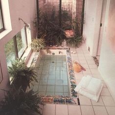 an indoor swimming pool with tiled flooring and plants in the window sill area