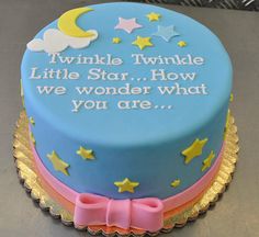 a blue cake with yellow stars and a pink bow on the top that says twinkle little star how we wonder what you are