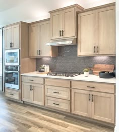 a kitchen with wooden cabinets and white counter tops, wood flooring and stainless steel appliances