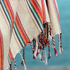 colorful striped fabric with tassels hanging from it's sides next to the ocean